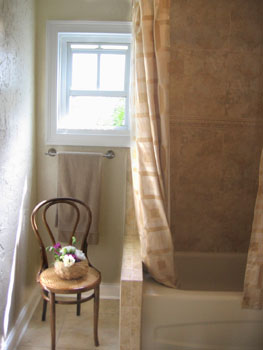 A bentwood chair graces the corner at the end of the tub.