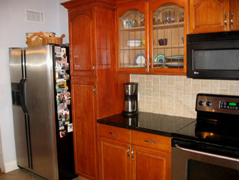 The kitchen has black granite counter tops and glass fronted cupboards.