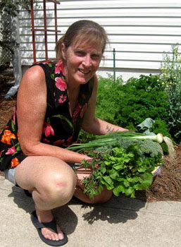 Ginny Stibolt with a bountiful spring harvest. The background is her wide-row garden.  
        Photo by Stibolt