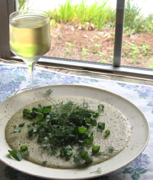 Cold Gold Potato soup with the herb garden in the background. Chives, meadow garlic and basil are visible.  Photo by Stibolt